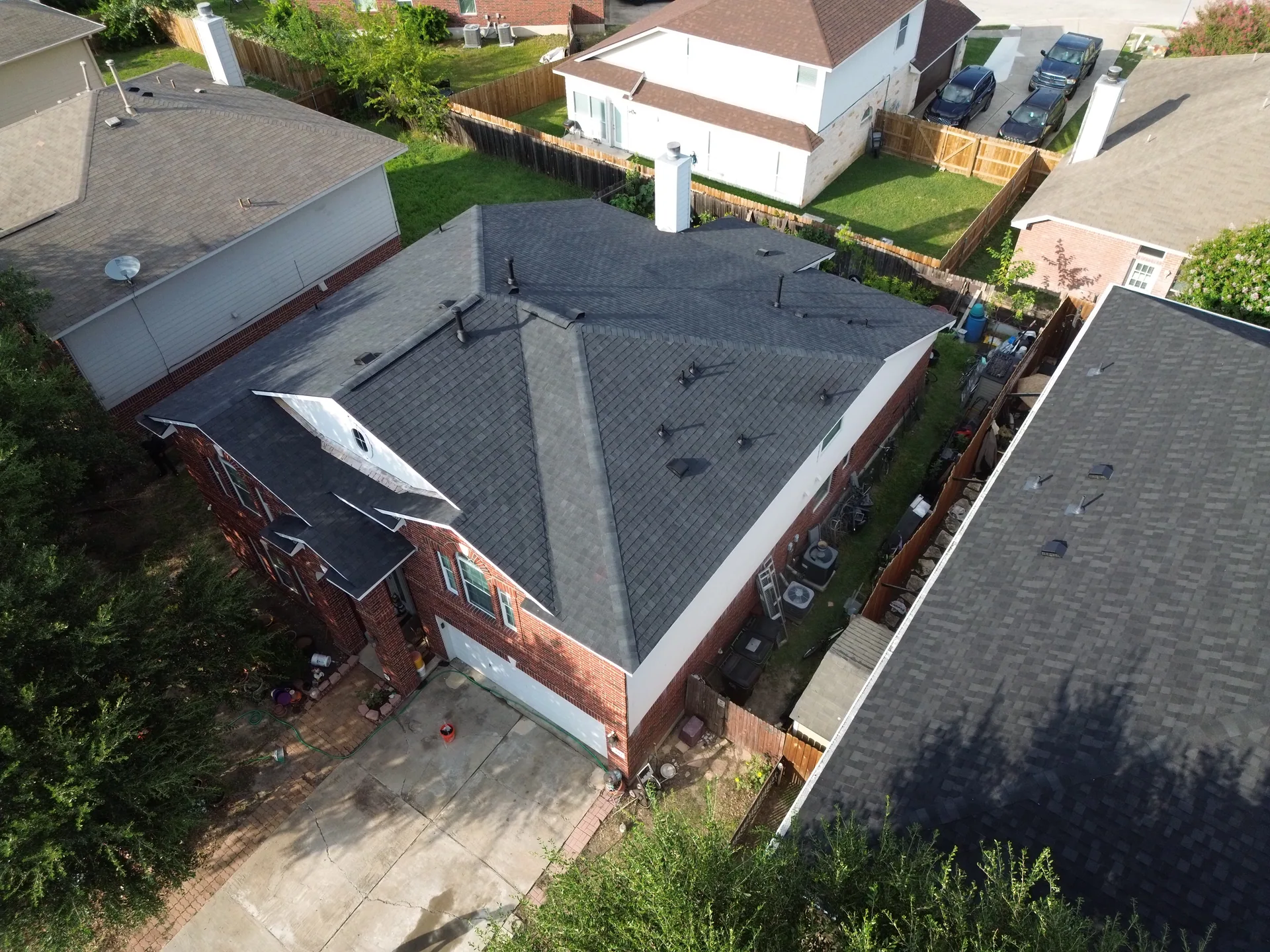 Aerial brick home charcoal shingle roof chimney, Hutto, TX