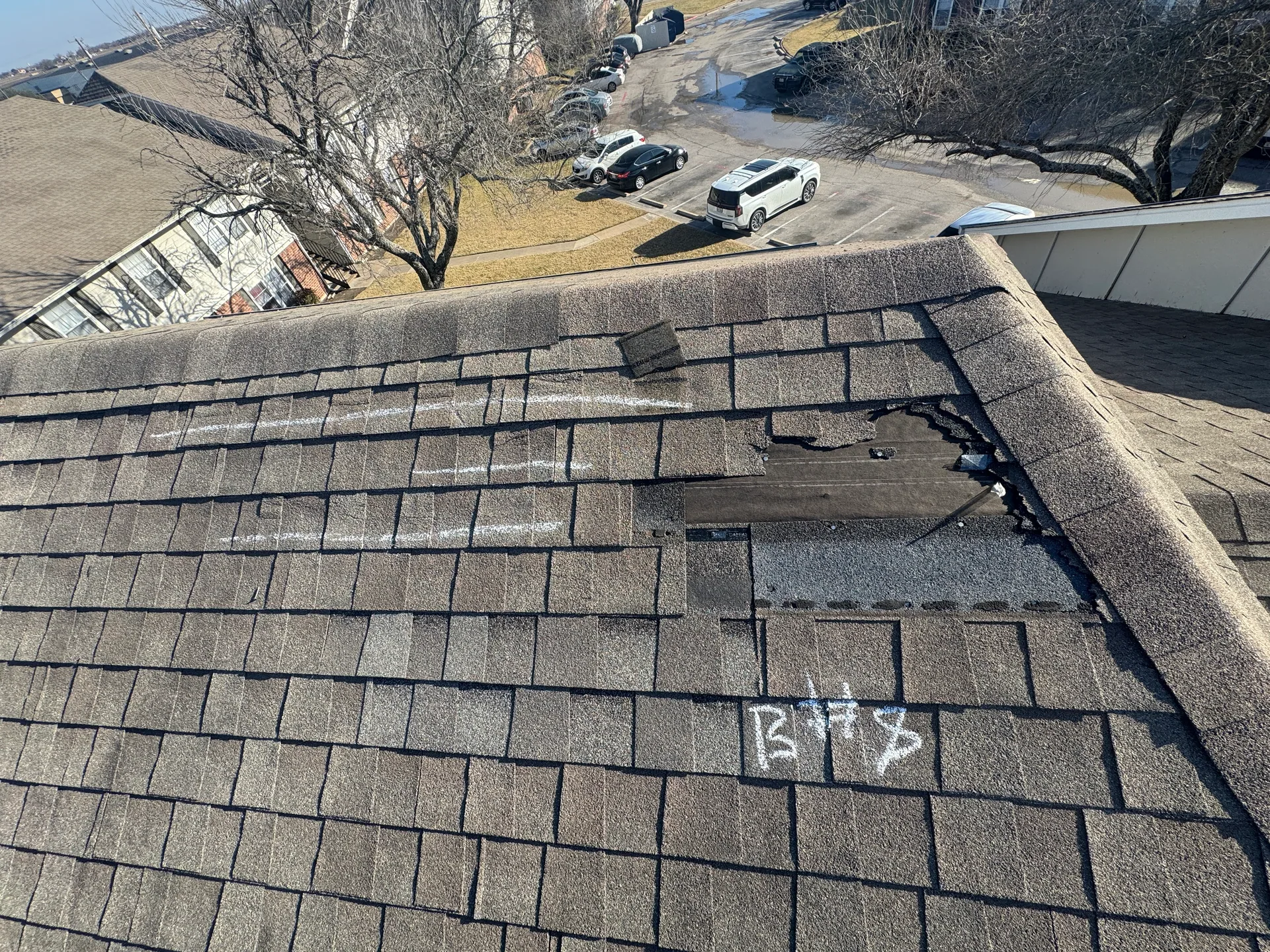 Wind torn missing shingles apartment roof, Hutto, TX